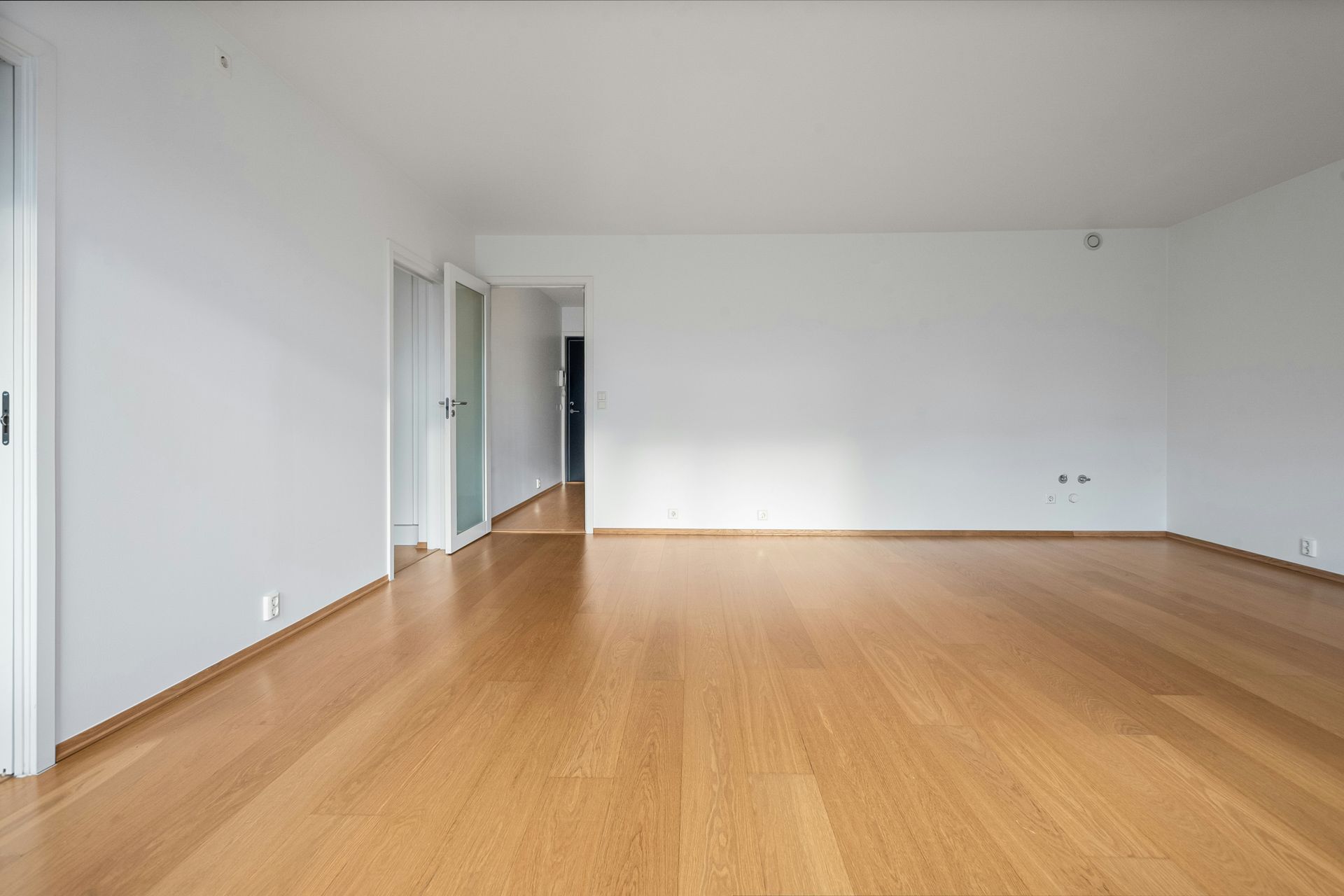 An empty room with hard wood floors and white walls